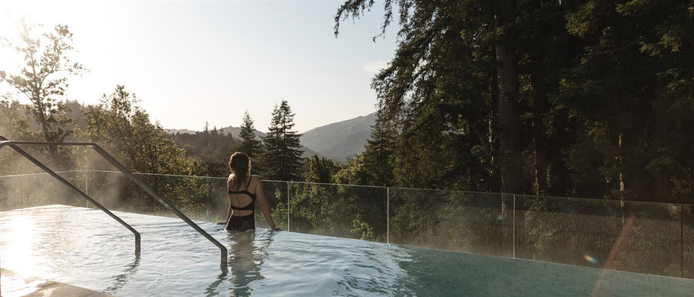 Woman in pool overlooking expansive green landscape
