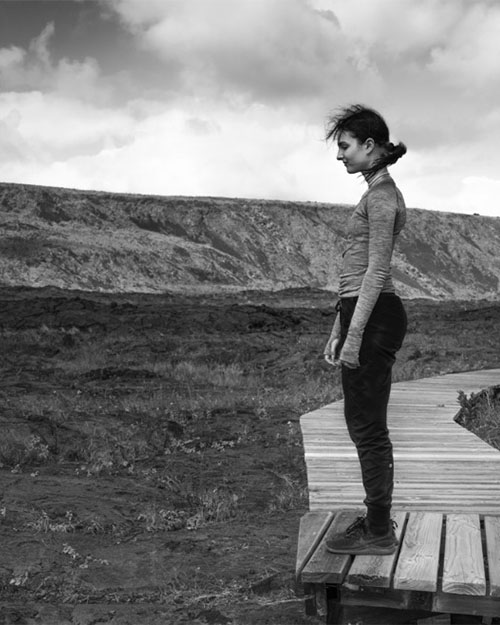 A woman standing on a wooden deck with mountain backdrop